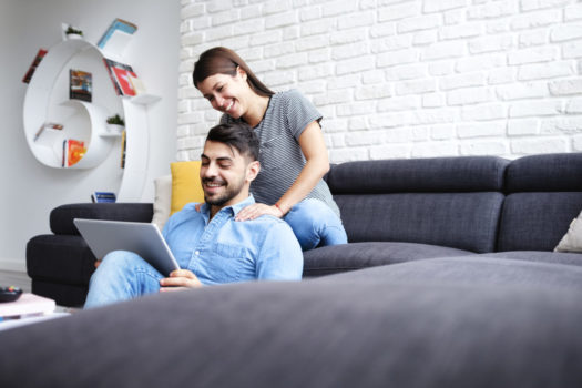 Girl Massaging Boyfriend On Sofa At Home